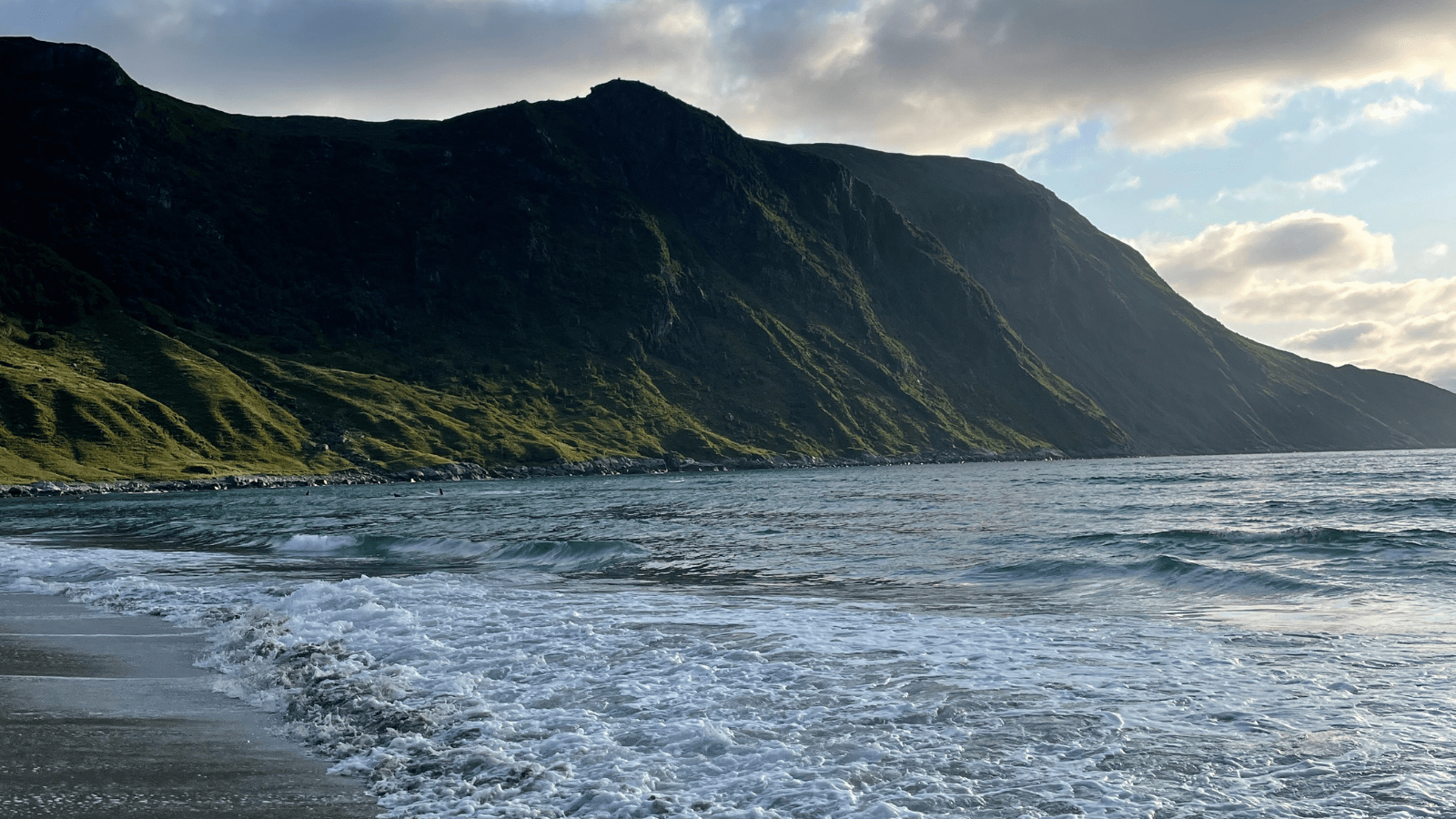 Strand med fjell i bakgrunn